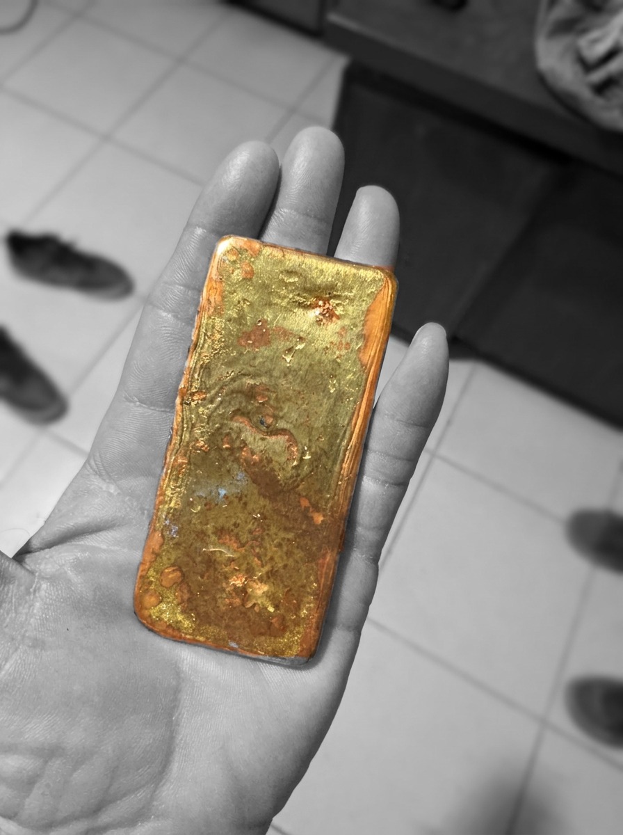 A freshly produced gold bar held in hand